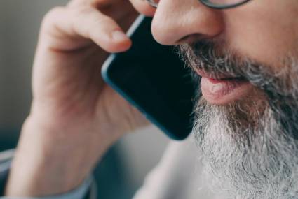 Brodaty mężczyzna rozmawia przez telefon.